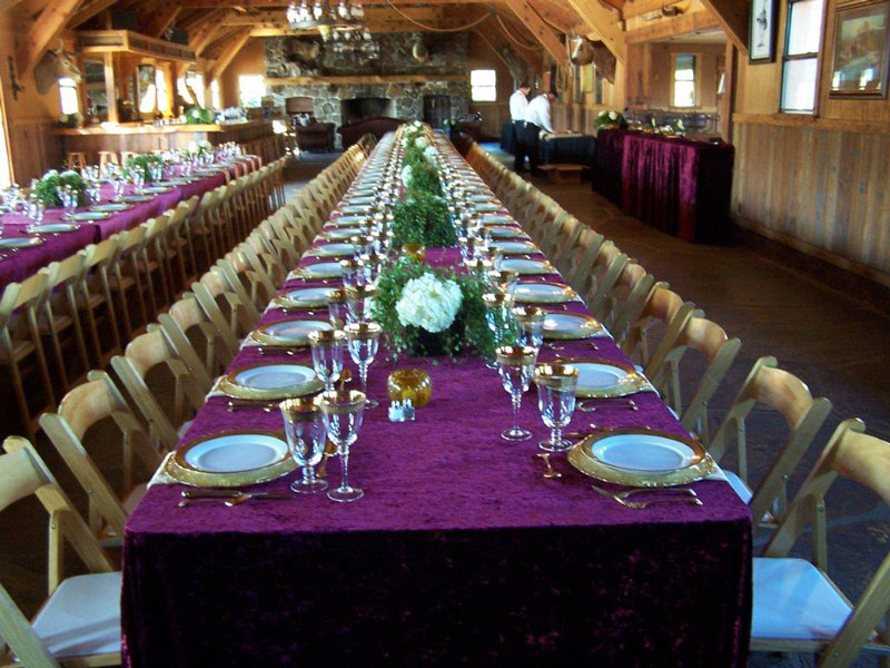 long tables set up at hearst castle with burgundy tablecloths and gold edged plates 