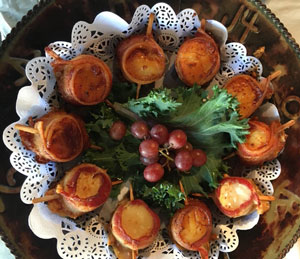 plate of bacon wrapped scallops on wood skewers