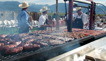 variety of meats cooking on grill with three men brushing on sauce