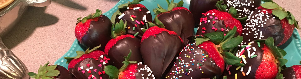 a plate of chocolate covered strawberries on a serving table