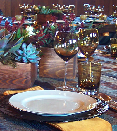 closeup of tablesetting on striped tablecloth with succulent centerpieces